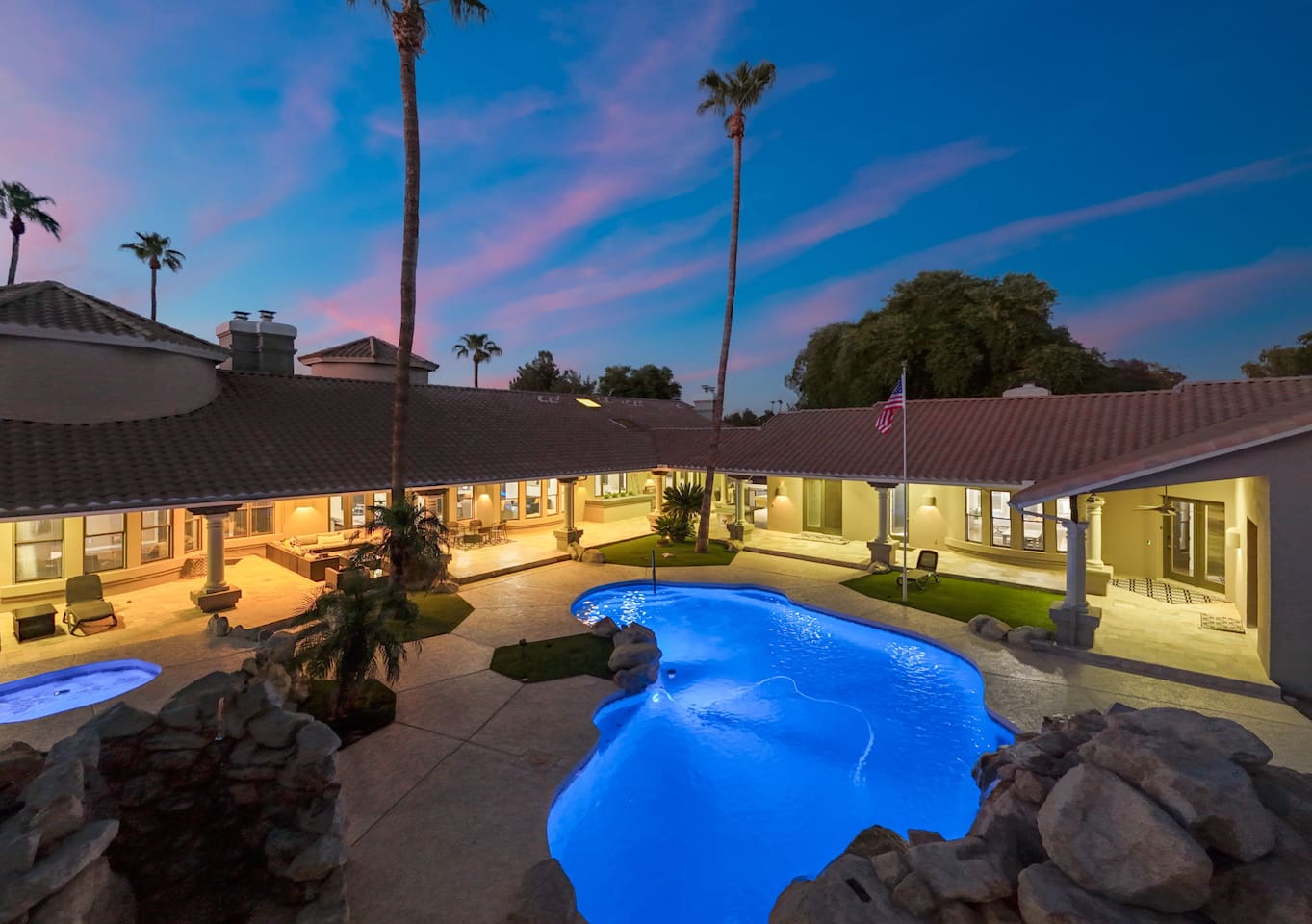 This expansive backyard transforms at dusk, with ambient lighting and a sparkling pool setting the mood.

