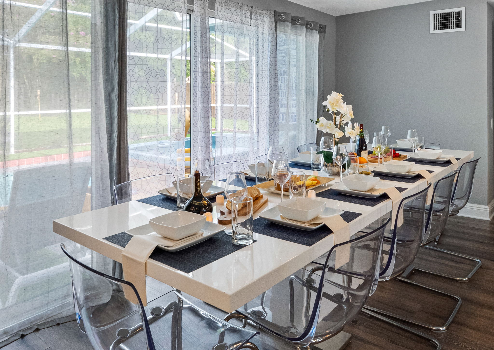 With its glossy white dining table and acrylic chairs, this space exudes a clean, minimalist vibe that complements the home’s modern aesthetic.