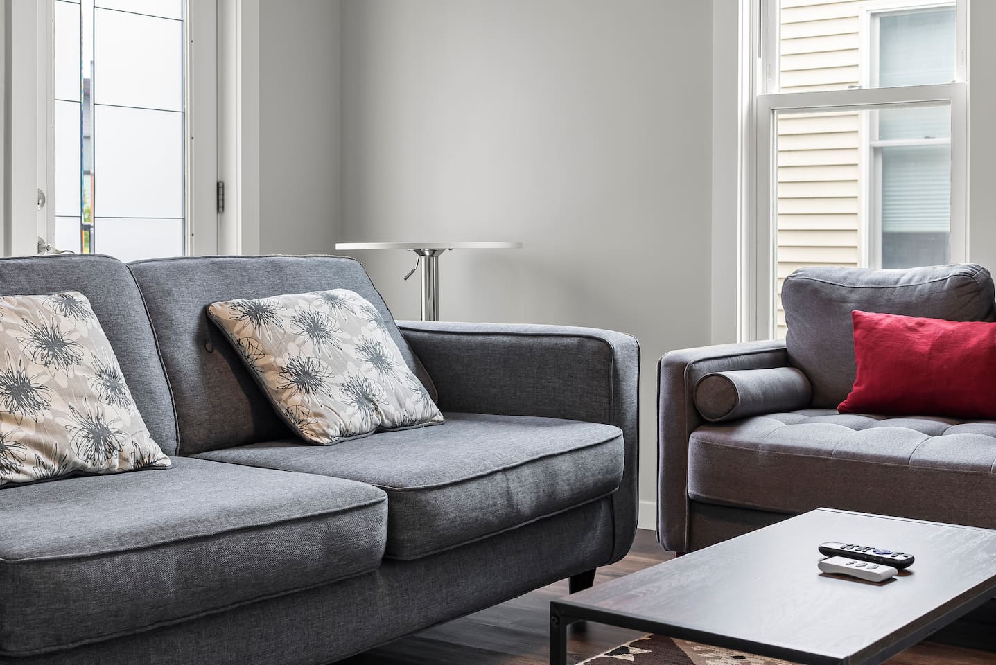 Relax on the tufted armchair accented with a bold red pillow and sleek glass lamp nearby.