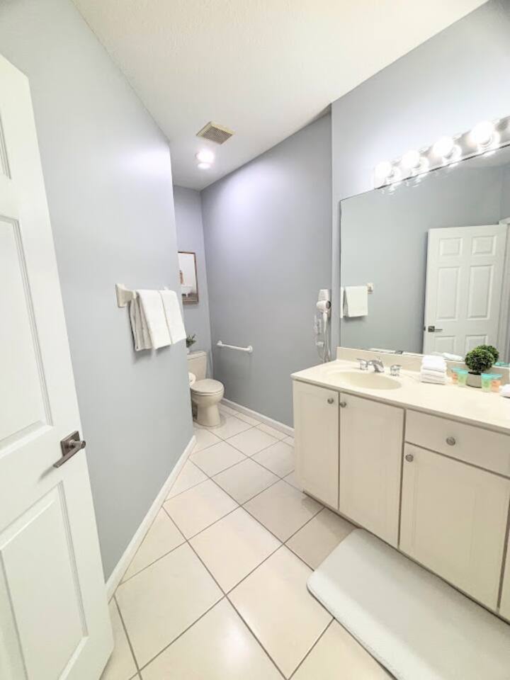 Clean and bright bathroom featuring a spacious vanity, large mirror, tile flooring, and neutral finishes.