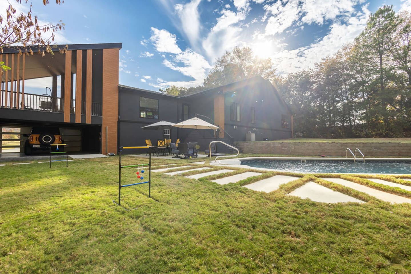 Spacious backyard featuring a refreshing pool, with a stunning view of the back exterior of the house, creating the perfect space for outdoor relaxation and entertainment.