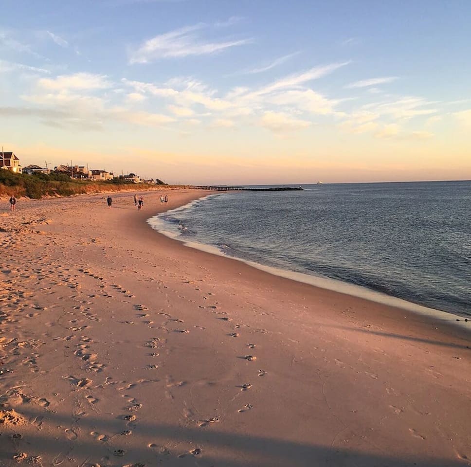 Unwind with a peaceful stroll along the shore. The expansive sandy beach is bathed in the warm glow of sunset, offering a quiet escape just moments from your stay.