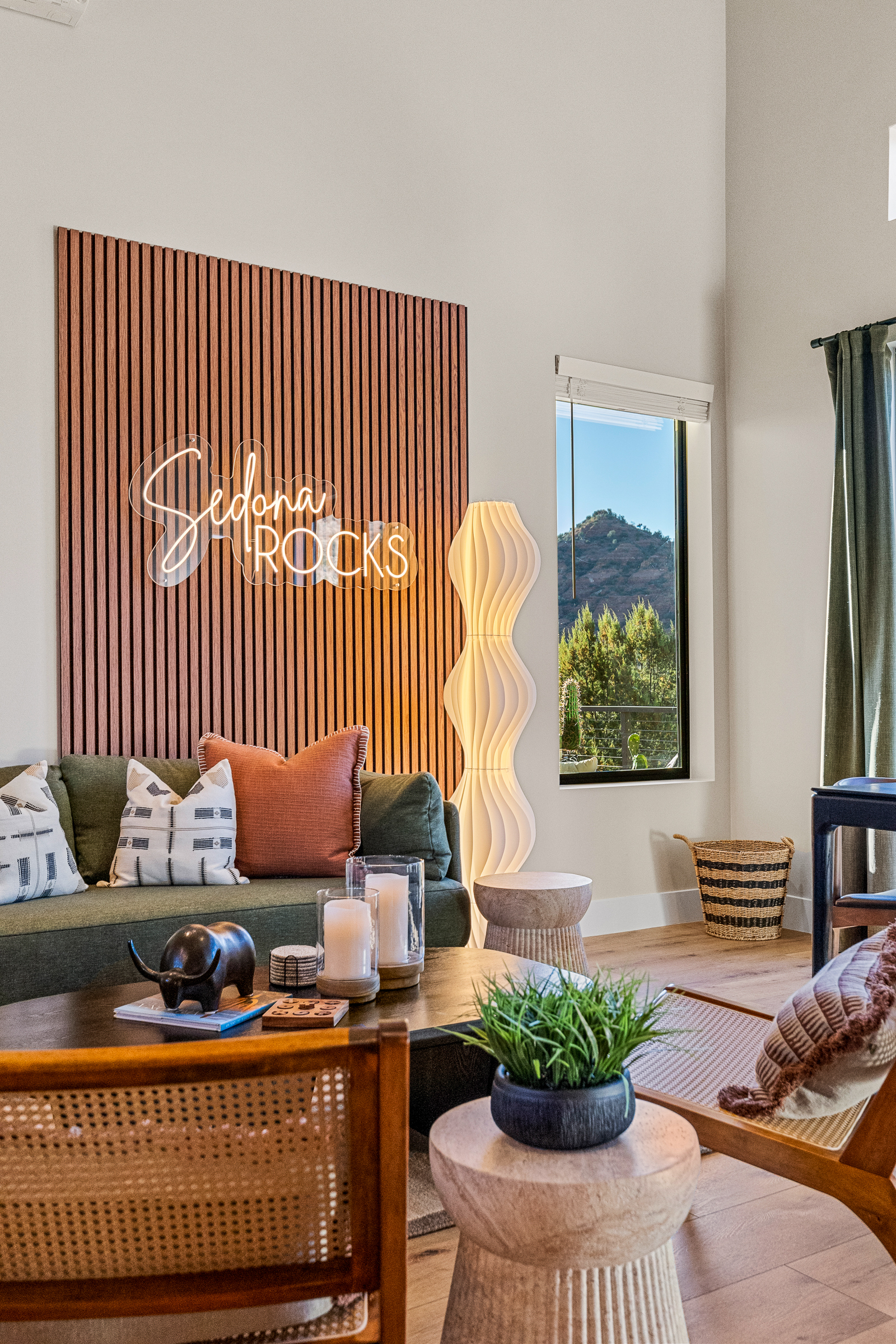 Layered textures, soft lighting, and thoughtful decor create a comfortable living space, with views of Sedona's Pyramid Rock visible just beyond the windows.