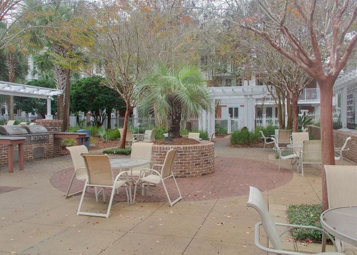 Pilot House courtyard patio with tables, grills and pergola shaded by trees