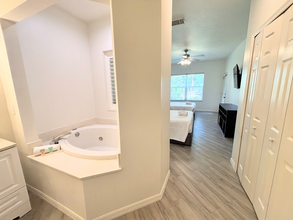 Bedroom and bathroom entry area with soaking tub access, closet space, and updated flooring.
