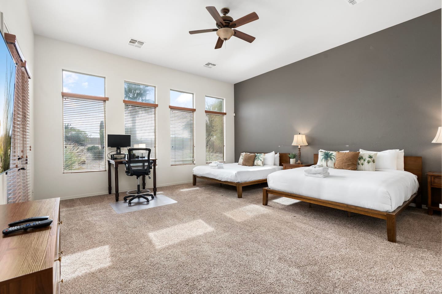 Spacious master bedroom featuring two king beds, plush linens, and a dedicated workspace by the windows for remote work or planning your day.
