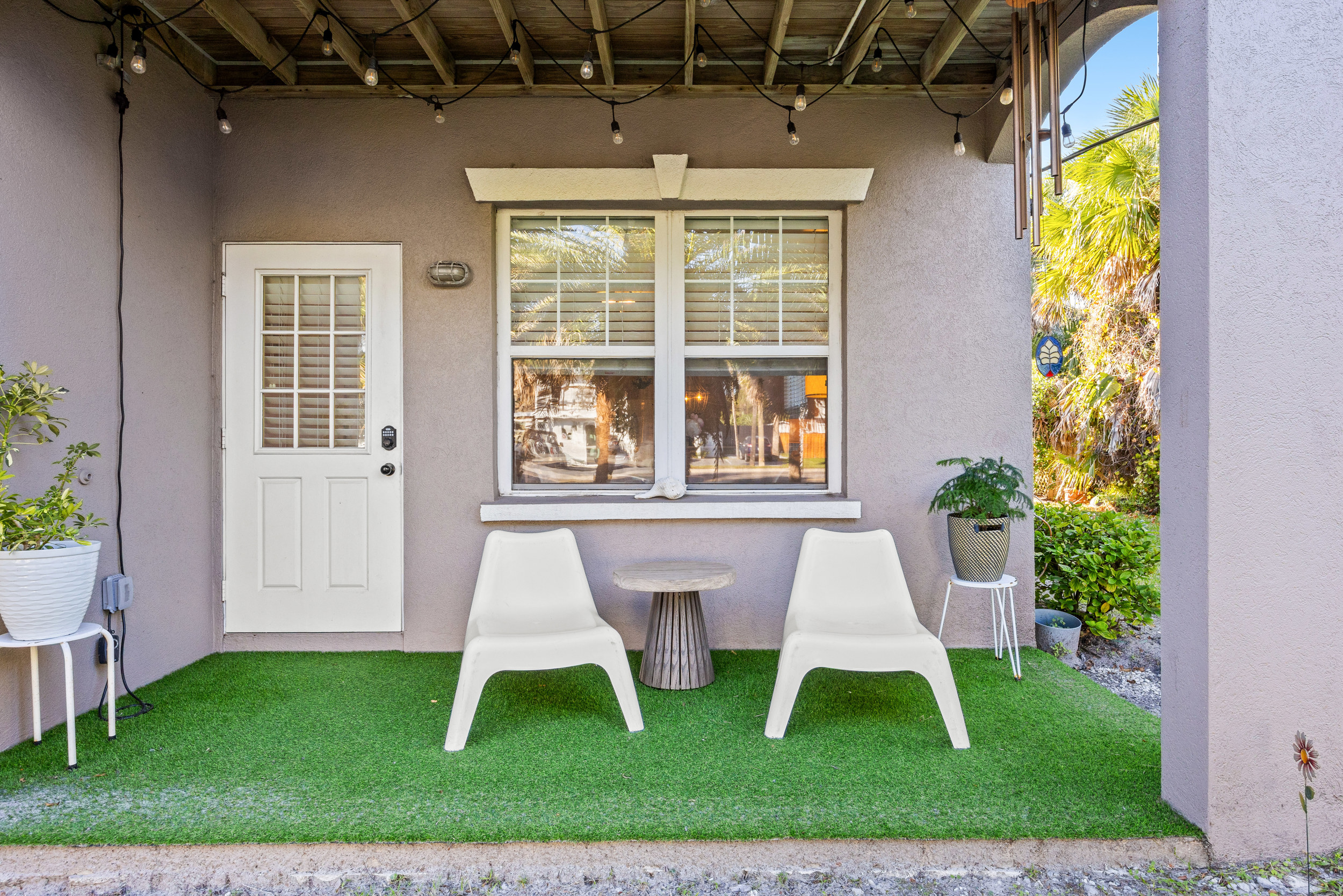 Cozy covered patio with string lights, modern seating, and lush greenery — the perfect spot to unwind.