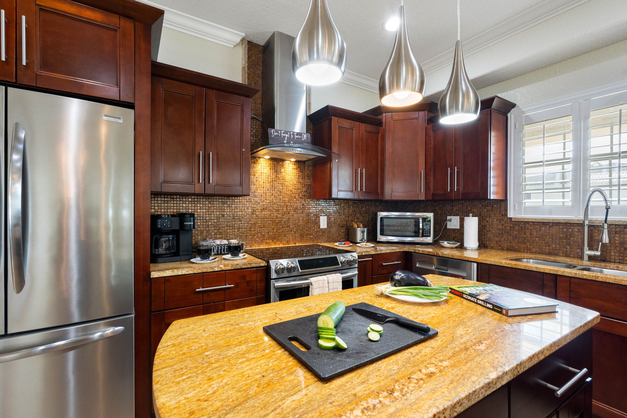 From the refrigerator to the range hood, stainless steel finishes complement the rich tones of the cabinetry and backsplash.