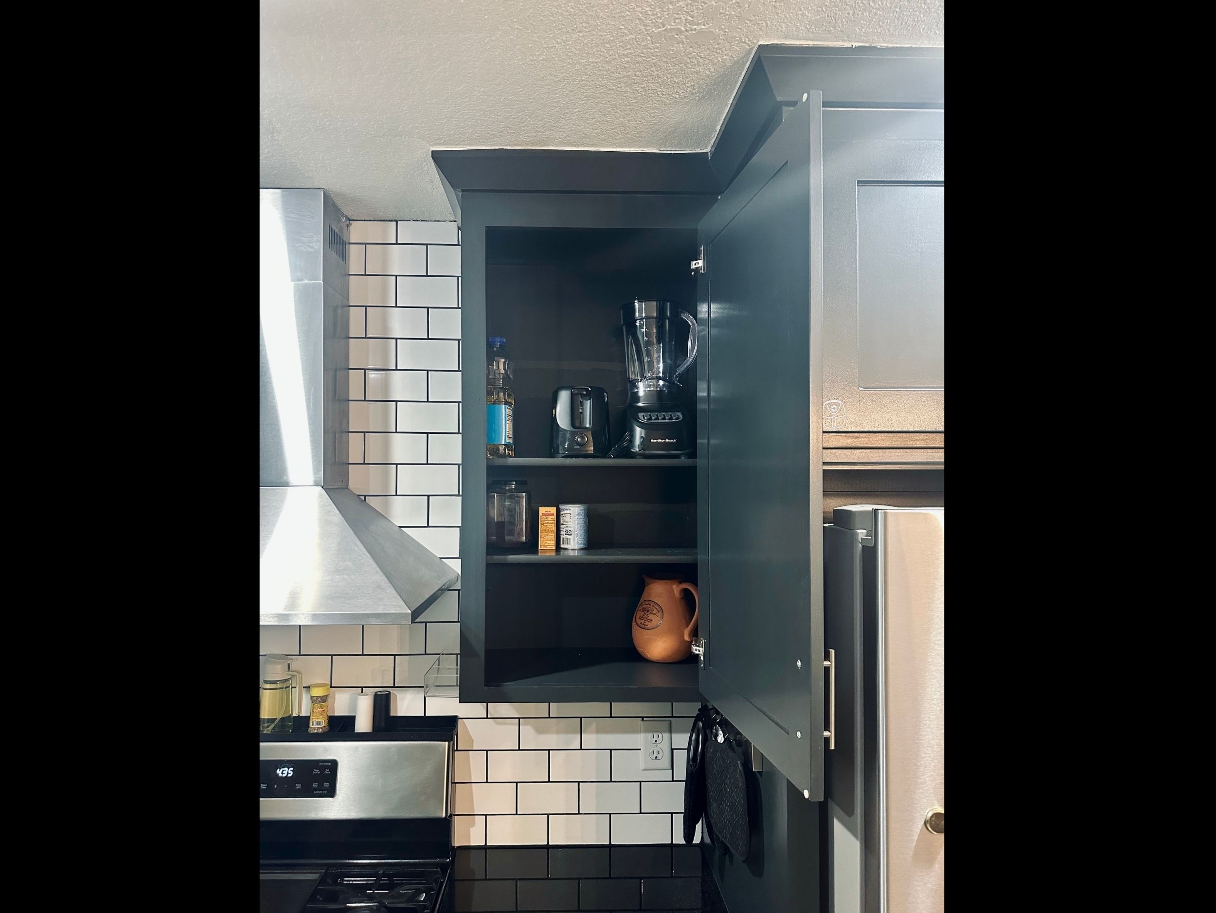 Kitchen cabinet featuring small appliances including a blender, toaster, and pitcher, along with essential cooking and baking staples.