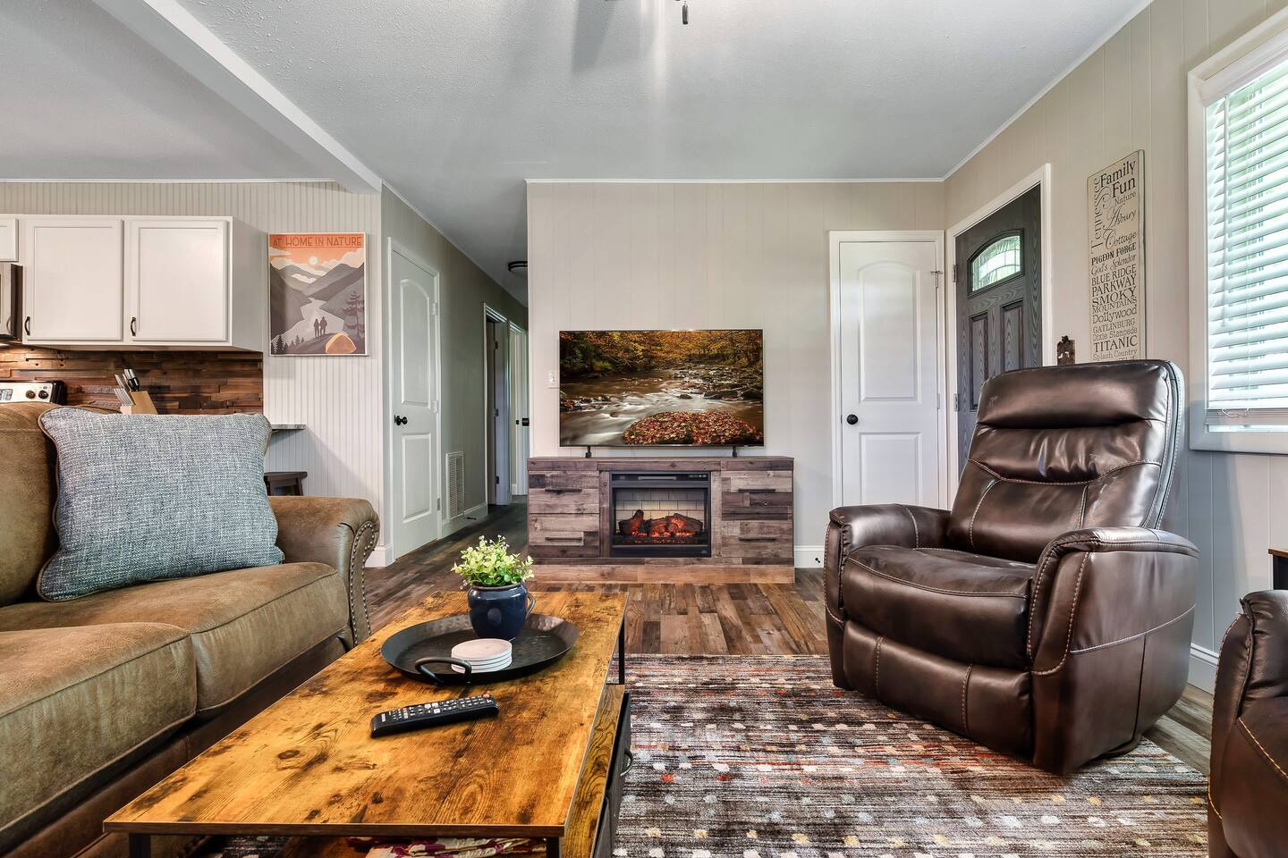 Cozy up to the warmth of the electric fireplace in the inviting living room, featuring plush recliners and a soothing ambiance. #FiresideMoments