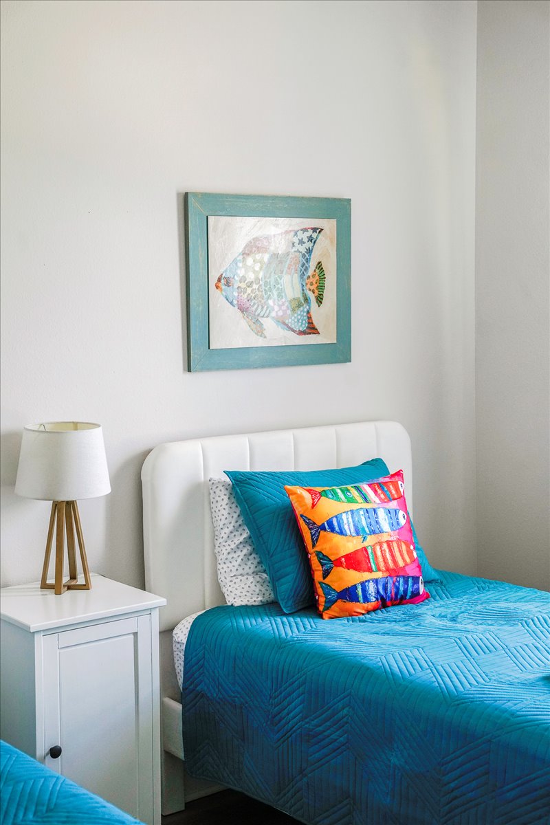 Relax in this charming Twin Bedroom with soft linens, nightstand, and a lamp