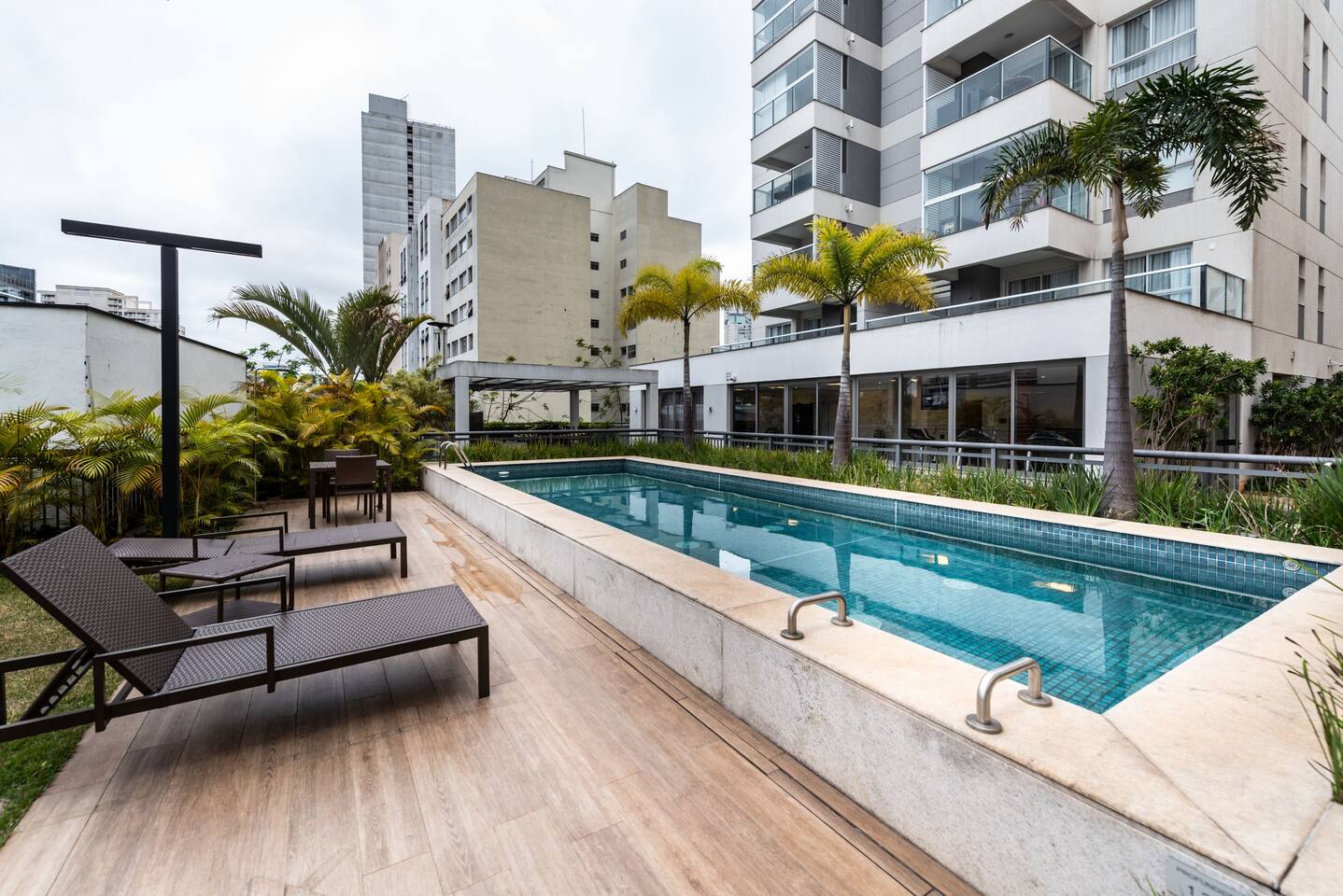 Piscina moderna com espreguiçadeiras e deck para relaxar.