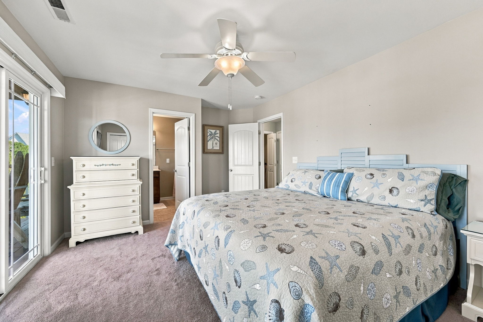 Rest easy in this inviting king bedroom with coastal-inspired bedding, soft carpeting, and plenty of natural light