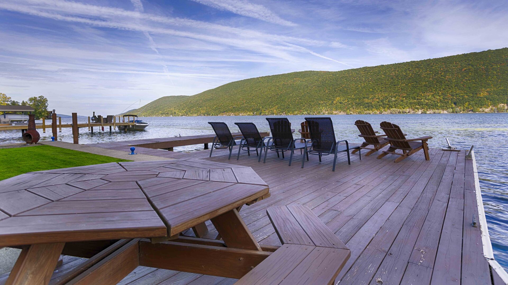 Set against the backdrop of tranquil waters, this picturesque dock features a beautiful dining area perfect for outdoor meals or gatherings. A large, sturdy dining table sits in the center, surrounded by comfortable, weather-resistant chairs with plu
