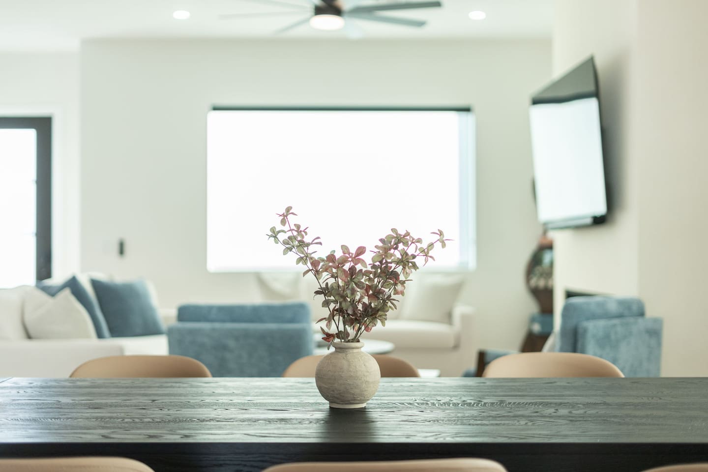 Stylish dining table with a rustic vase centerpiece, set against the bright and airy living area.