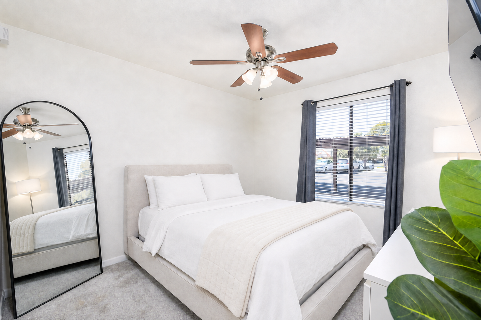 Bedroom with a queen bed, dresser, ceiling fan, and natural light for a comfortable rest.