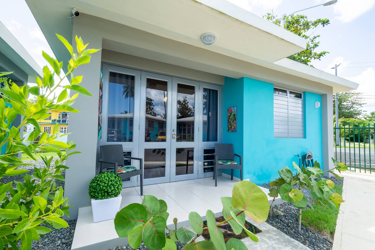 Front Porch: Unwind on stylish seating amid vibrant local art and lush greenery!