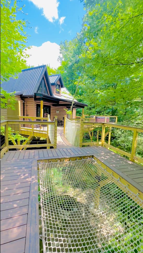 This unique treehouse deck offers a luxurious outdoor experience with an elevated hot tub and XL hammock seamlessly built into the deck floor. Additionally, enjoy the refreshing outdoor shower while surrounded by nature, making it a perfect retreat.