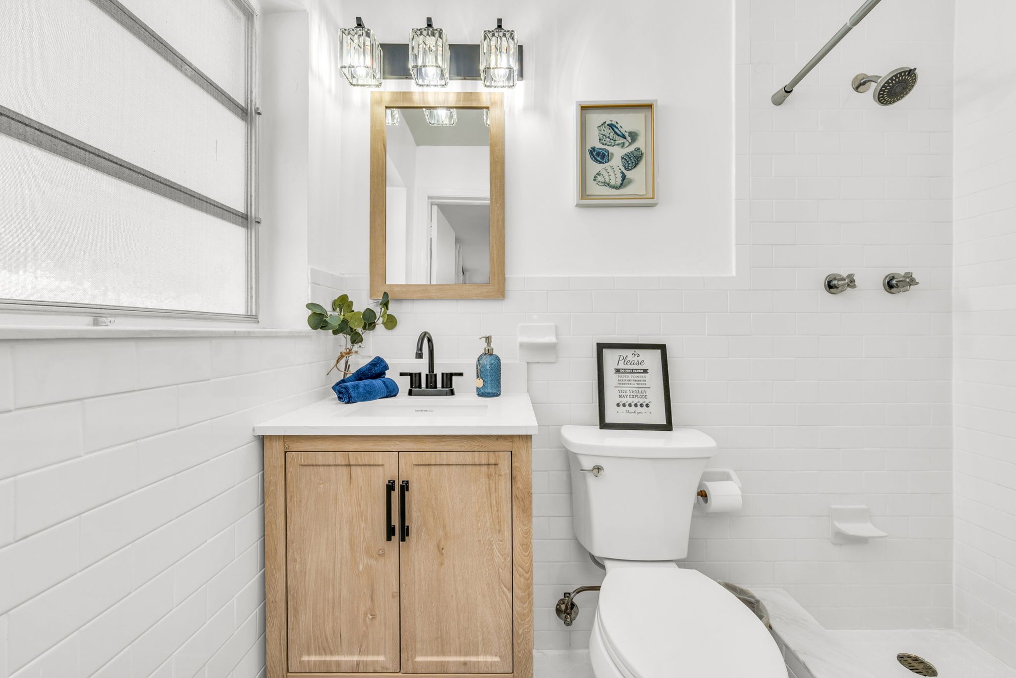A serene, spa-like ensuite showcasing a chic wood vanity, elegant lighting, modern black hardware, and a pristine walk-in shower for total comfort.