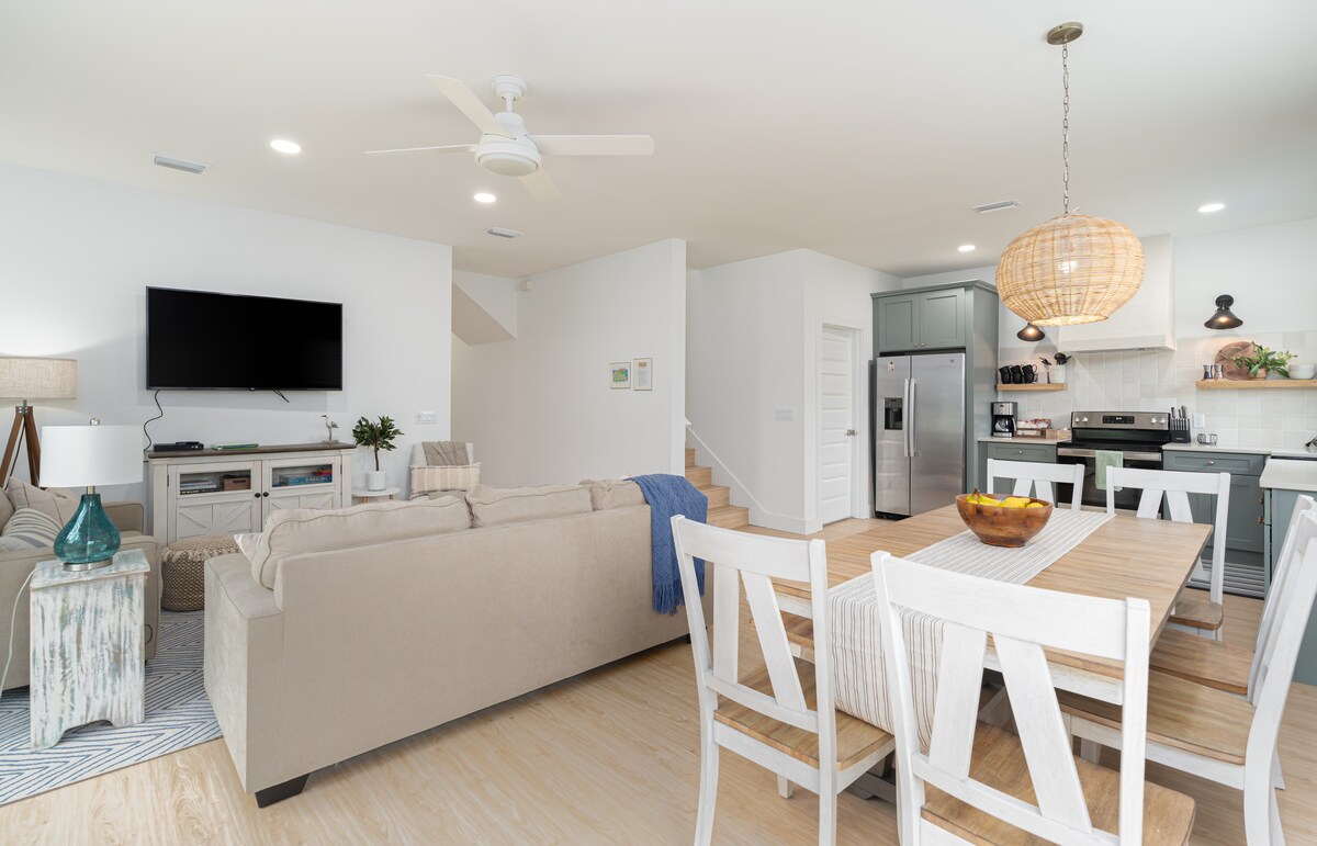 Stand at the foot of the stairs and you can take in the whole main floor at once - kitchen, table, sofas, TV. It is the kind of layout where nobody has to shout to be heard, and nobody gets left out of the plan.