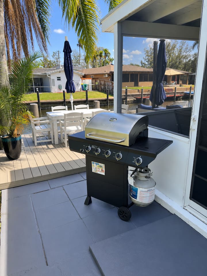 Outdoor gas grill beside the waterfront deck and dining area, perfect for easy cookouts by the canal.