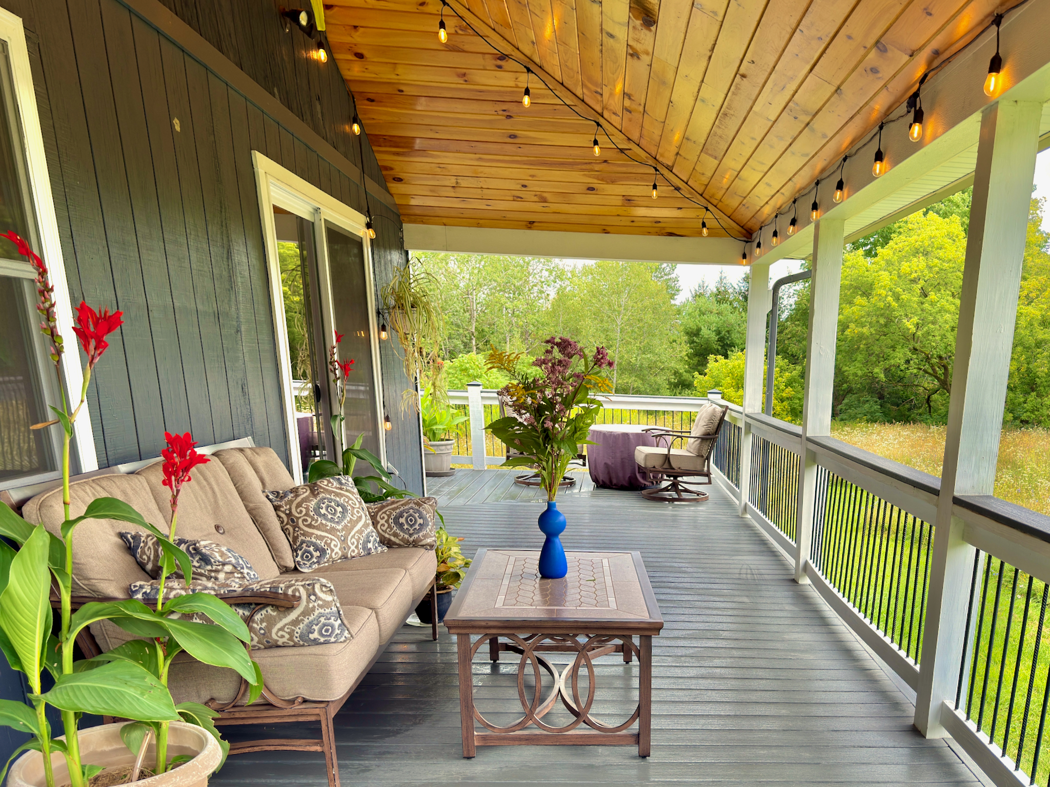 Covered deck with fire pit, cozy seating, and stunning pond and meadow views.
