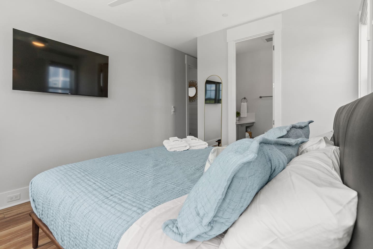 Thoughtful details make every stay more comfortable. This bedroom features a full-length mirror, brand new luxury linens and towels, and a 55-inch smart TV - everything you need to relax, refresh, and feel at home.