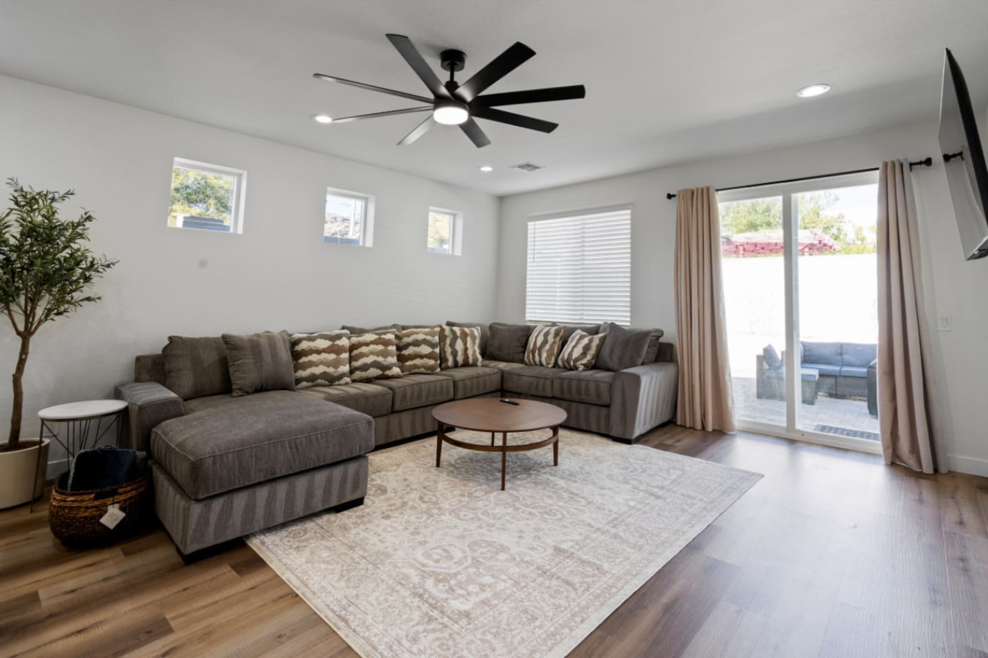 Living room with oversized sectional seating, ceiling fan, natural light, and plenty of space to relax or gather.
