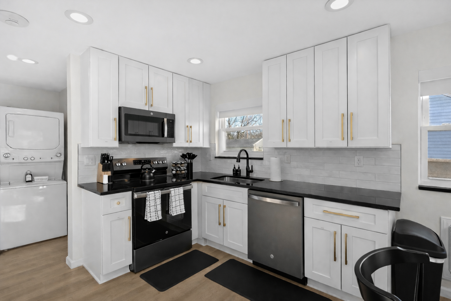 Bright, modern kitchen with crisp white cabinetry, sleek appliances, and in-unit laundry—designed for effortless cooking, convenience, and comfort.