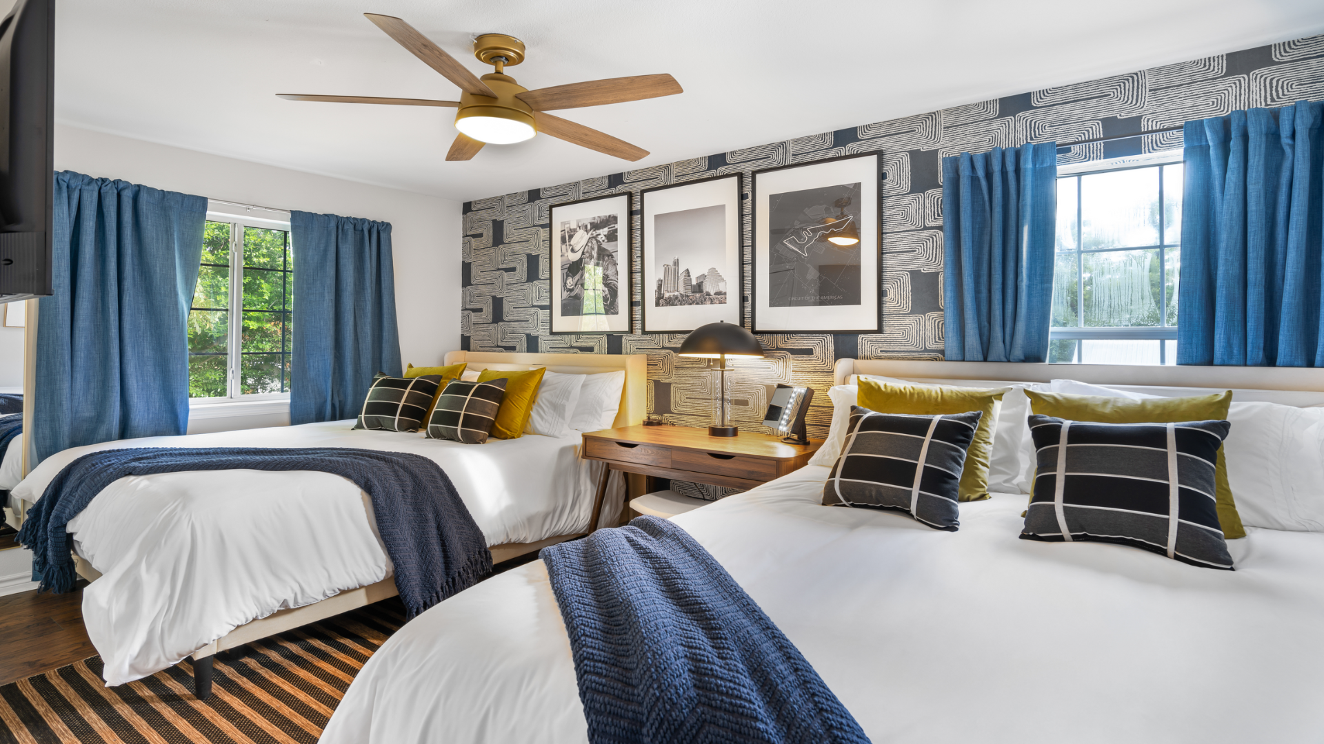 A perfect blend of style & comfort! Two plush beds with crisp white linens, navy & mustard accents, bold geometric wallpaper, and modern lighting create an inviting space to unwind.