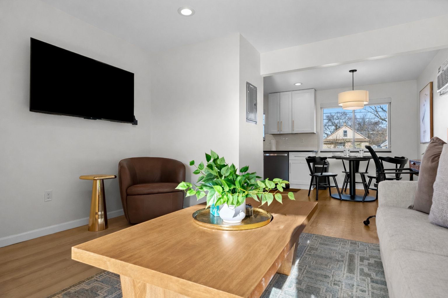 Open, airy living area with smart TV, cozy seating, and seamless flow into the kitchen and dining space—perfect for relaxing or sharing meals.