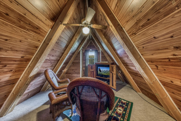 Relax in the cozy attic bedroom, complete with comfortable chairs and a TV — the perfect space to unwind and enjoy some downtime.