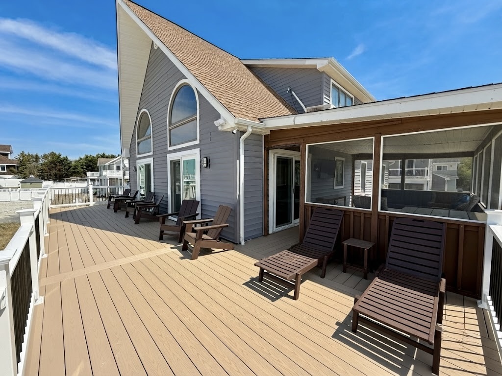 You can see an expansive outdoor deck featuring comfortable seating arrangements, including multiple lounge chairs and Adirondack-style chairs. This inviting space serves as an excellent spot for relaxing outside adjacent to the home.