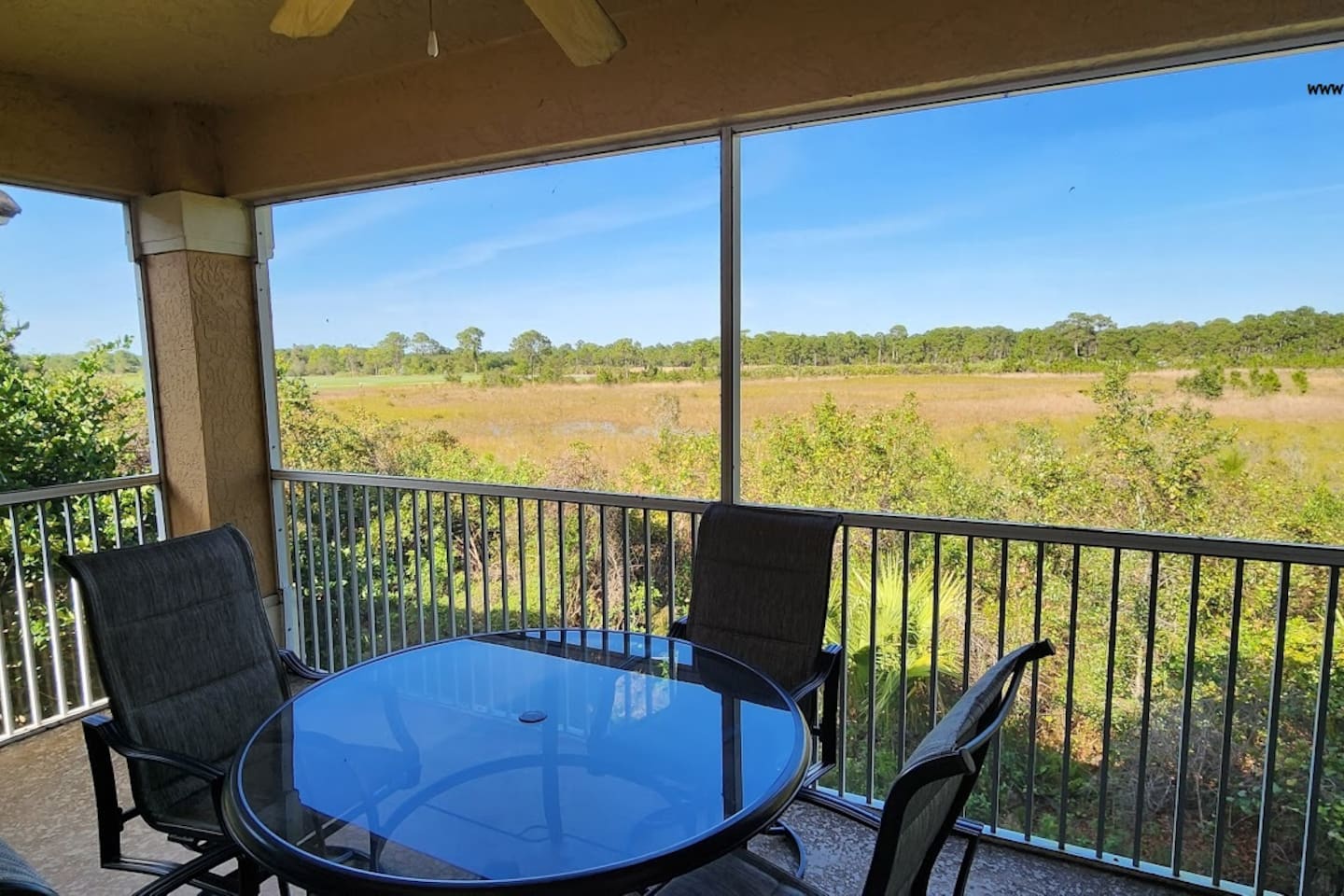 Private screened balcony with outdoor seating and peaceful views of the surrounding greenery.