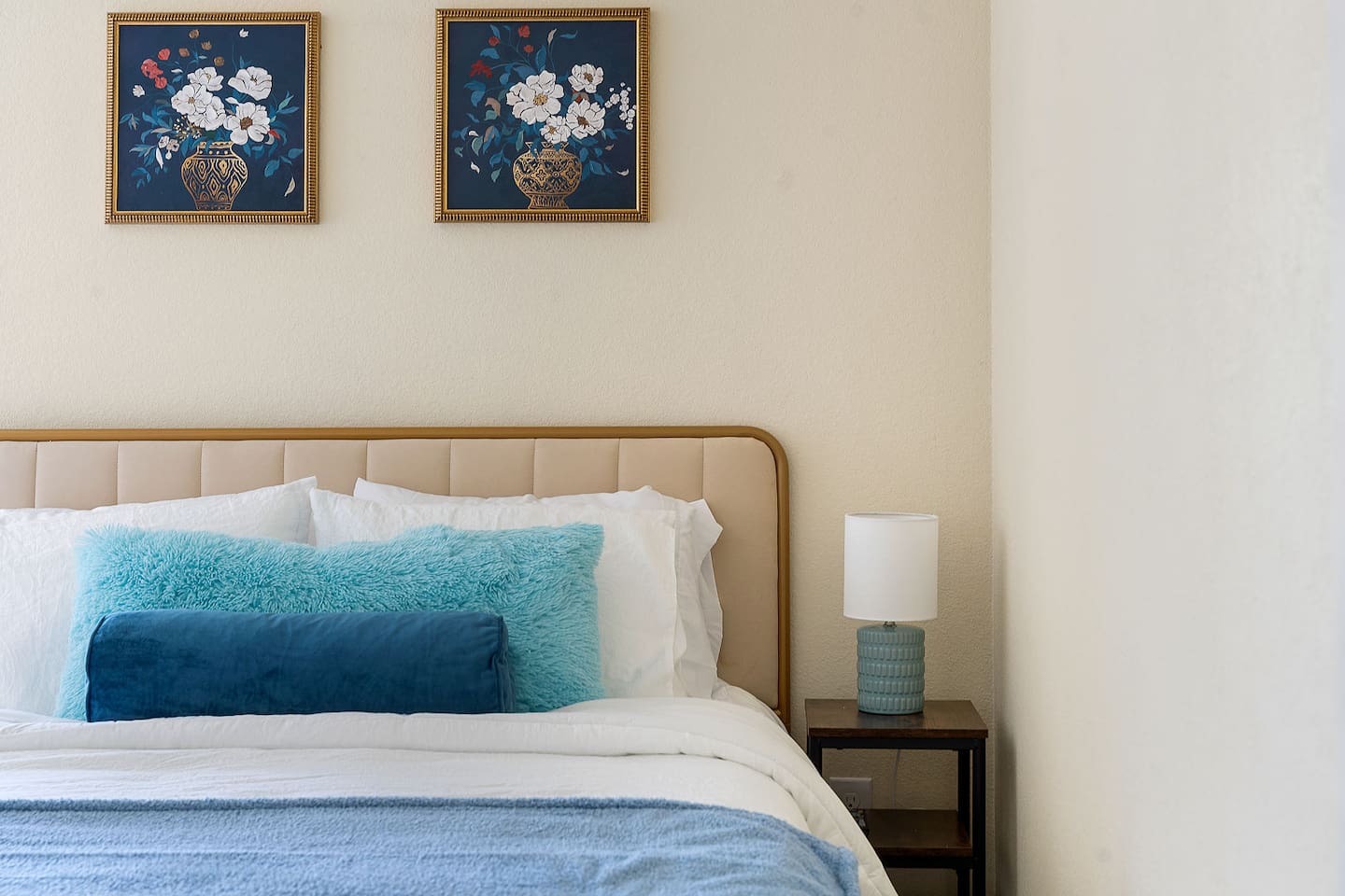 Discover this charming bedroom with vibrant floral artwork, a modern nightstand, and a stylish lamp.