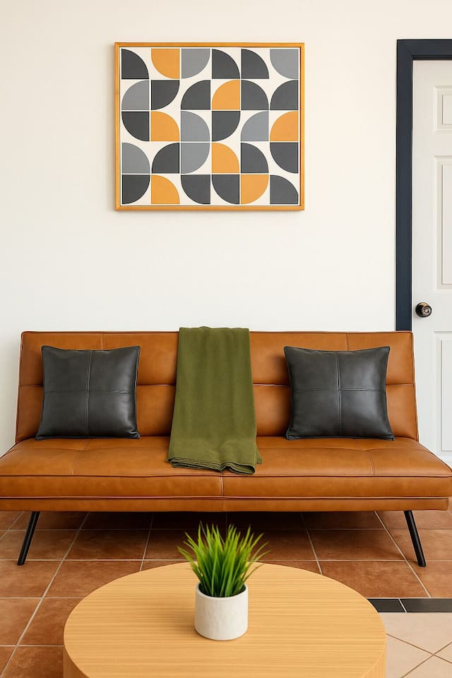 Cozy lounge with leather-style bench, greenery, and mid-century flair — a stylish corner for conversation. 