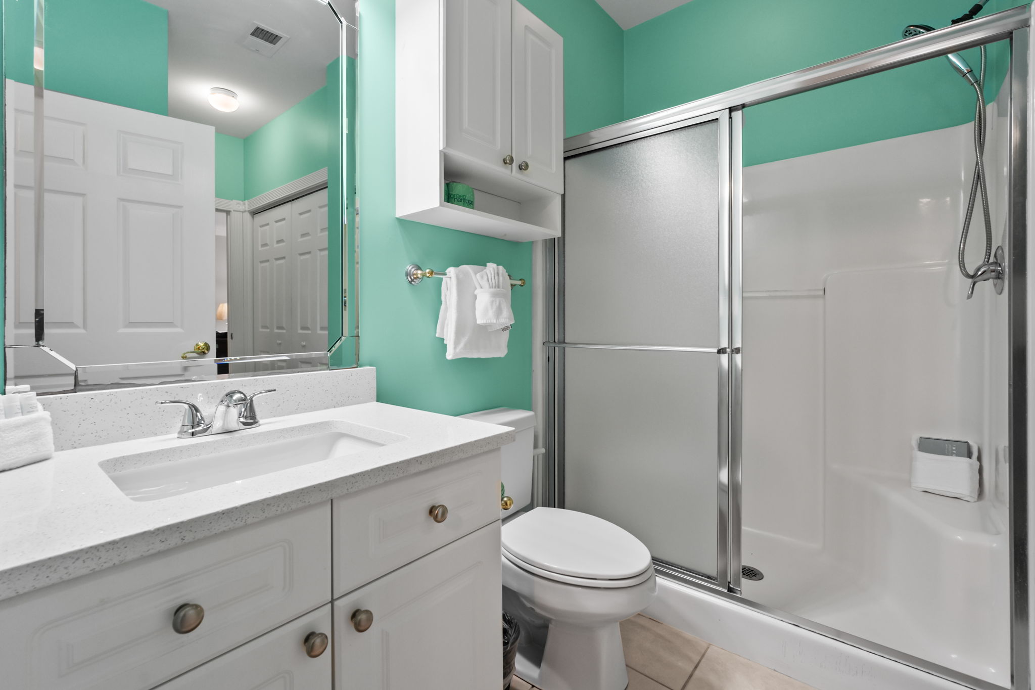 A modern washroom featuring a sleek glass partition, a bright white wooden cabinet, and coastally fixtures—combining functionality and simplicity for a refreshing experience.
