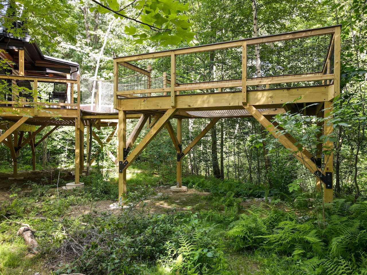 This unique treehouse deck offers a luxurious outdoor experience with an elevated hot tub and XL hammock seamlessly built into the deck floor. Additionally, enjoy the refreshing outdoor shower while surrounded by nature, making it a perfect retreat.