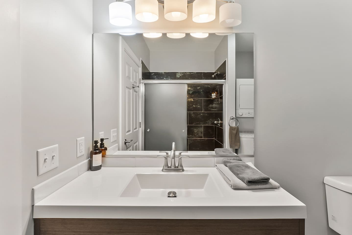 Bright and modern vanity with fresh towels and warm lighting for a welcoming touch.