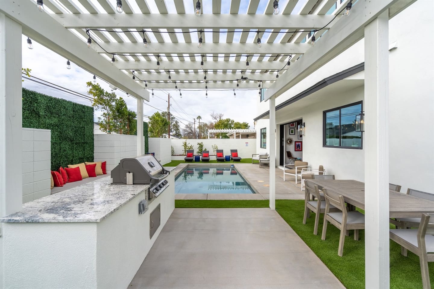 This inviting pergola showcases a grill and preparation area, creating an ideal outdoor cooking space, with a dining area nearby for enjoying delicious meals in style.