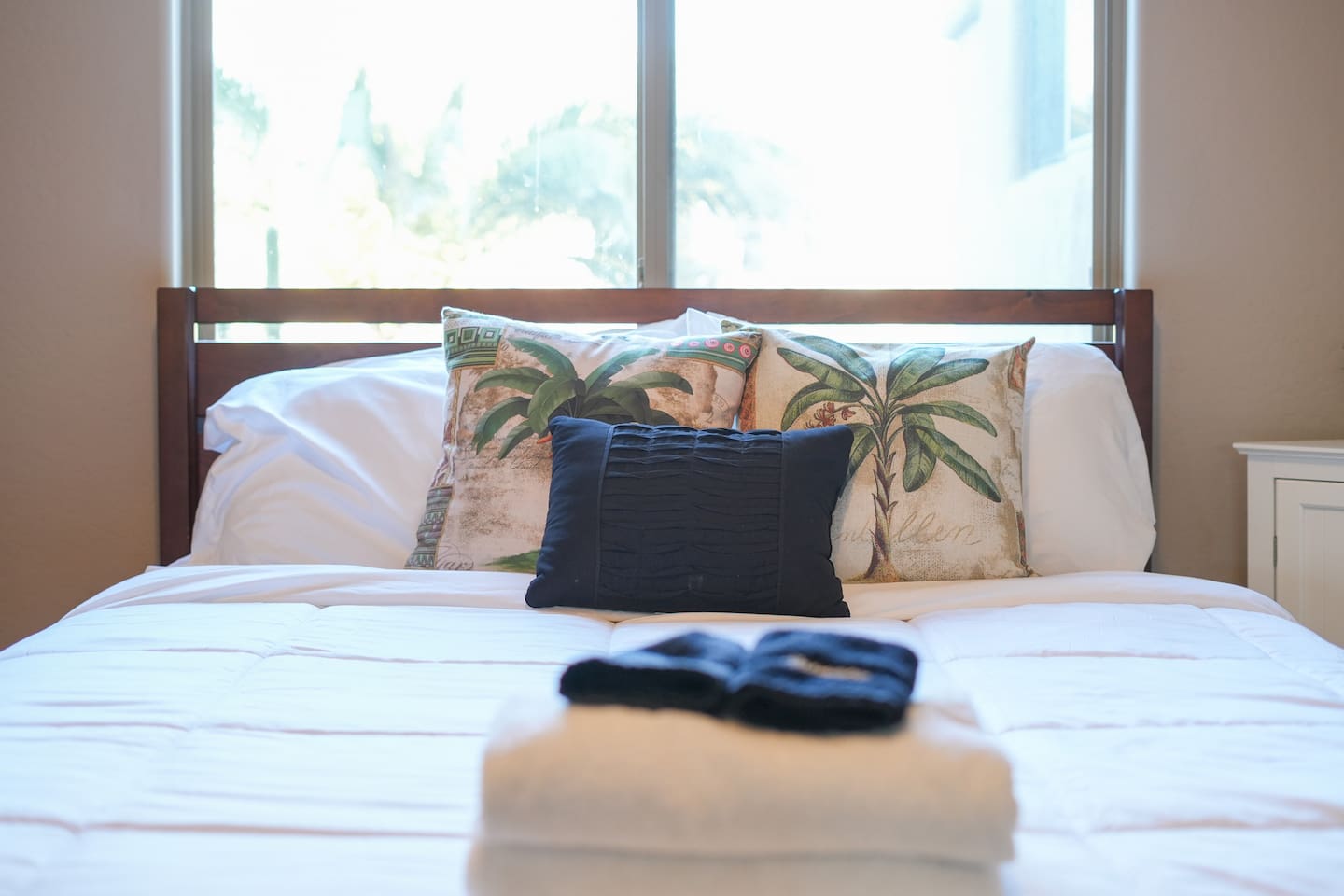Queen bed with fresh linens and palm-inspired accents for a relaxing stay.