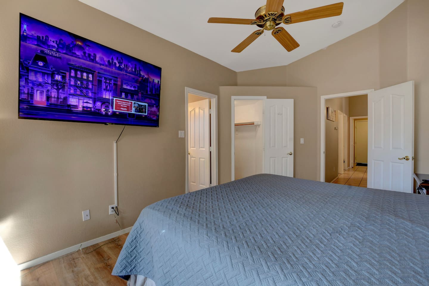 Cozy bedroom with 65-inch smart TV, ceiling fan, ensuite access