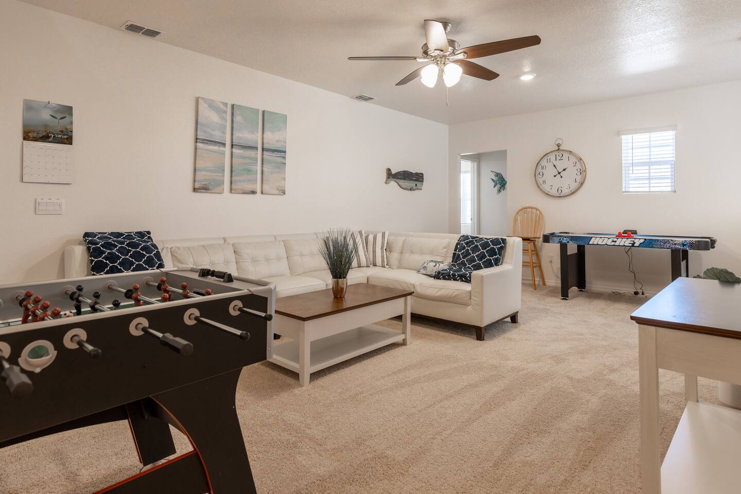 Upstairs lounge area with couch, 75in smart TV, overhead fan, air hockey table, foosball table and two player arcade game with thousands of games. 