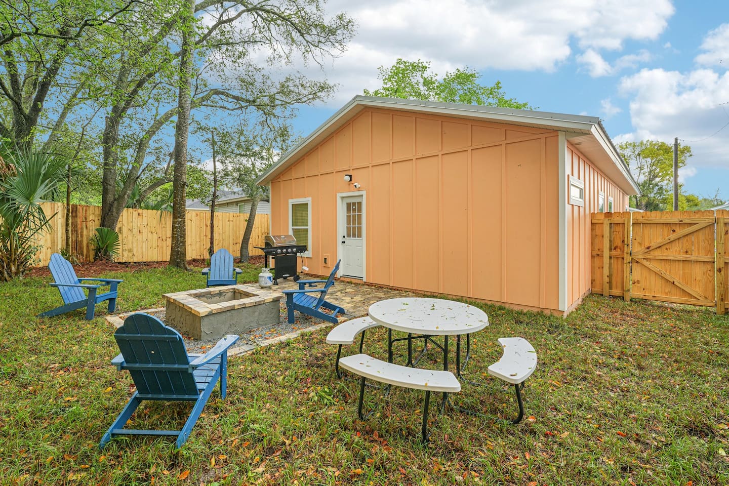 Outdoor area has a stone patio, stone fire pit, 4 adirondak-style chairs, and an 8-seat picnic table, with a fully fenced, private backyard.