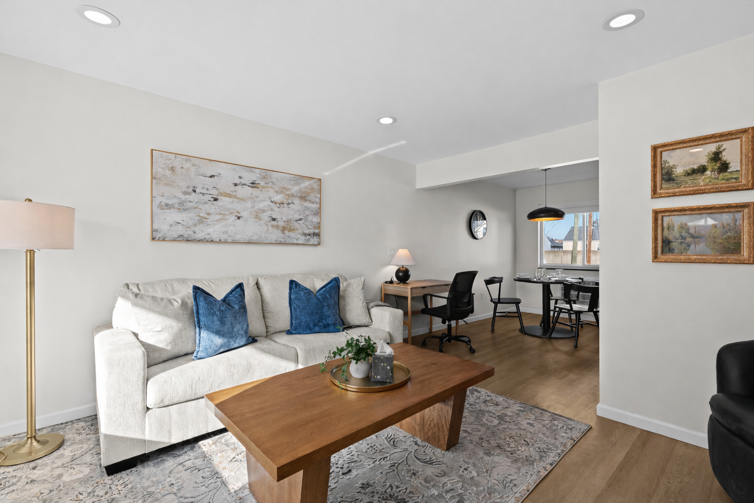 Sunlit living room with plush seating, stylish accents, and an open layout that flows into the dining and workspace—ideal for relaxing or working comfortably.