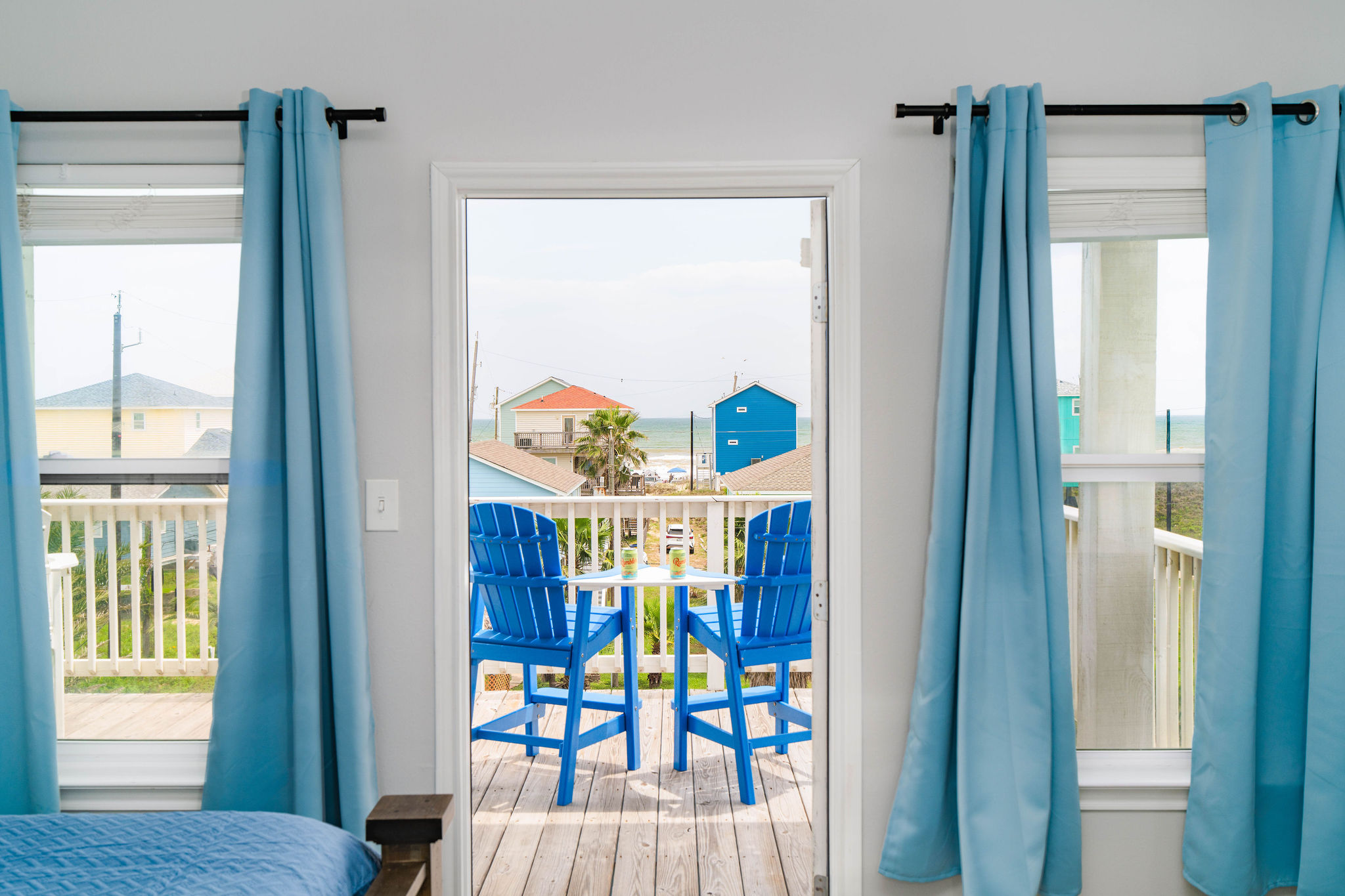 From the bedroom doorway — blue deck chairs framing the Gulf. Wake up to this view.
