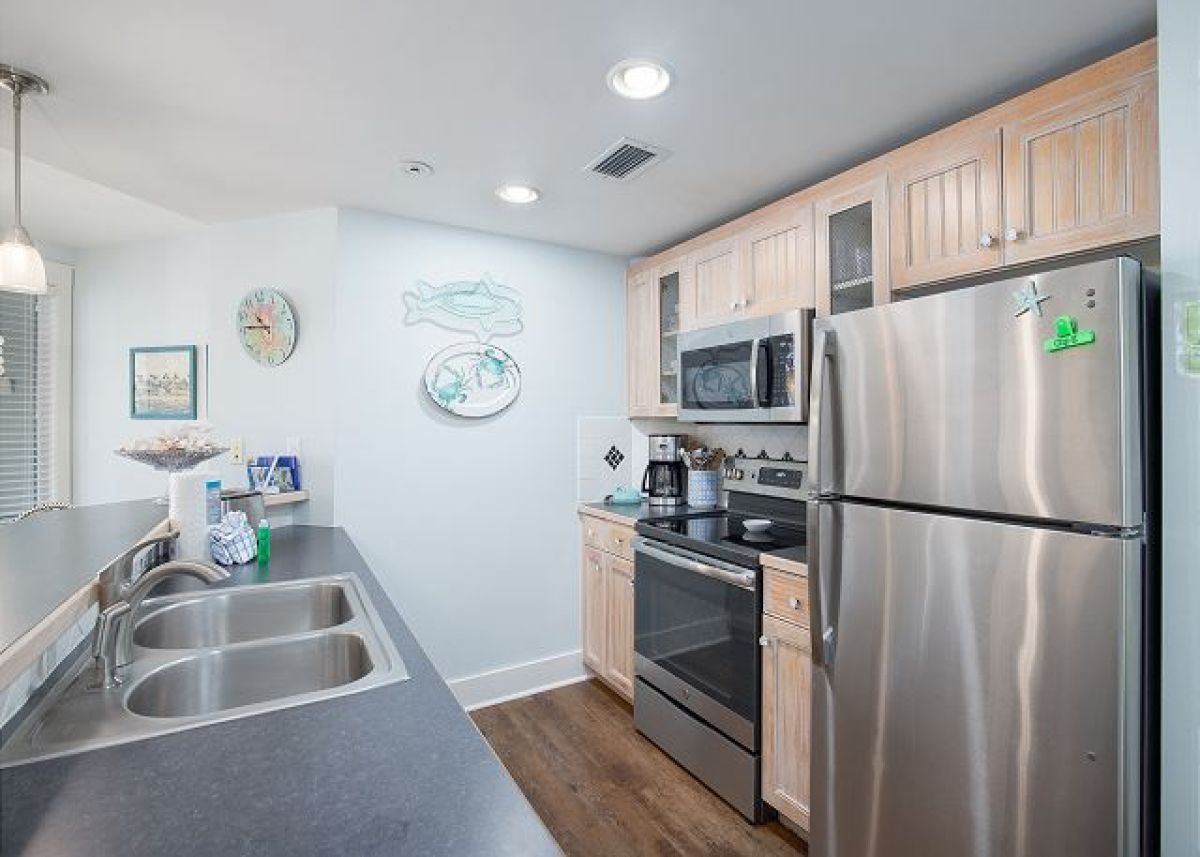 Full kitchen with stainless refrigerator, range and microwave, double sink and whitewashed cabinets