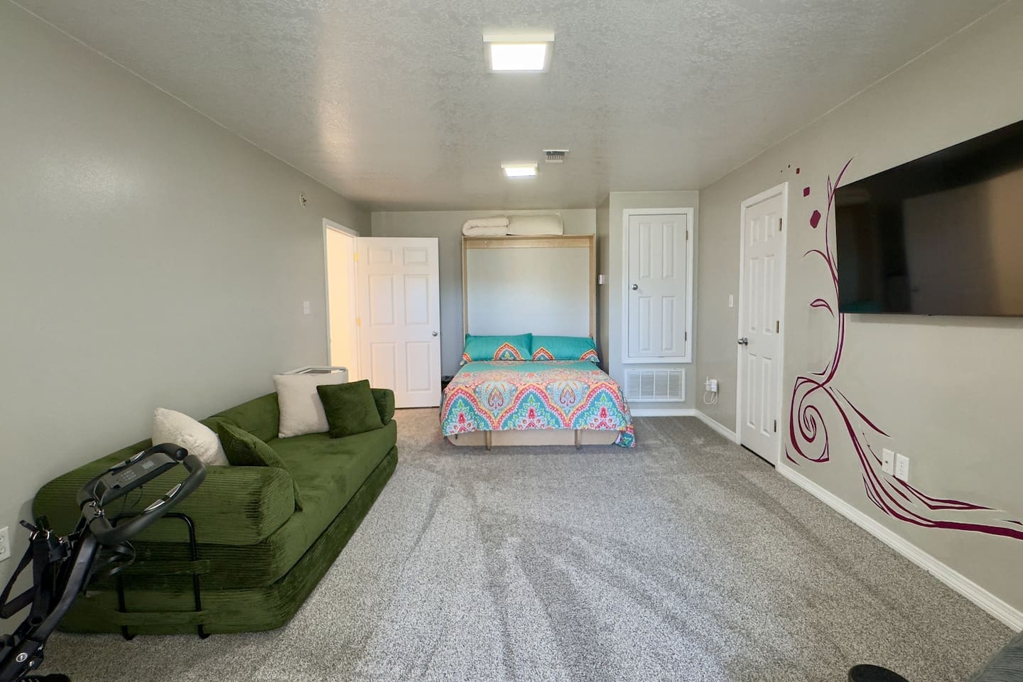 A Murphy bed with a colorful patterned bedspread folds neatly into a cabinet, maximizing room flexibility.
