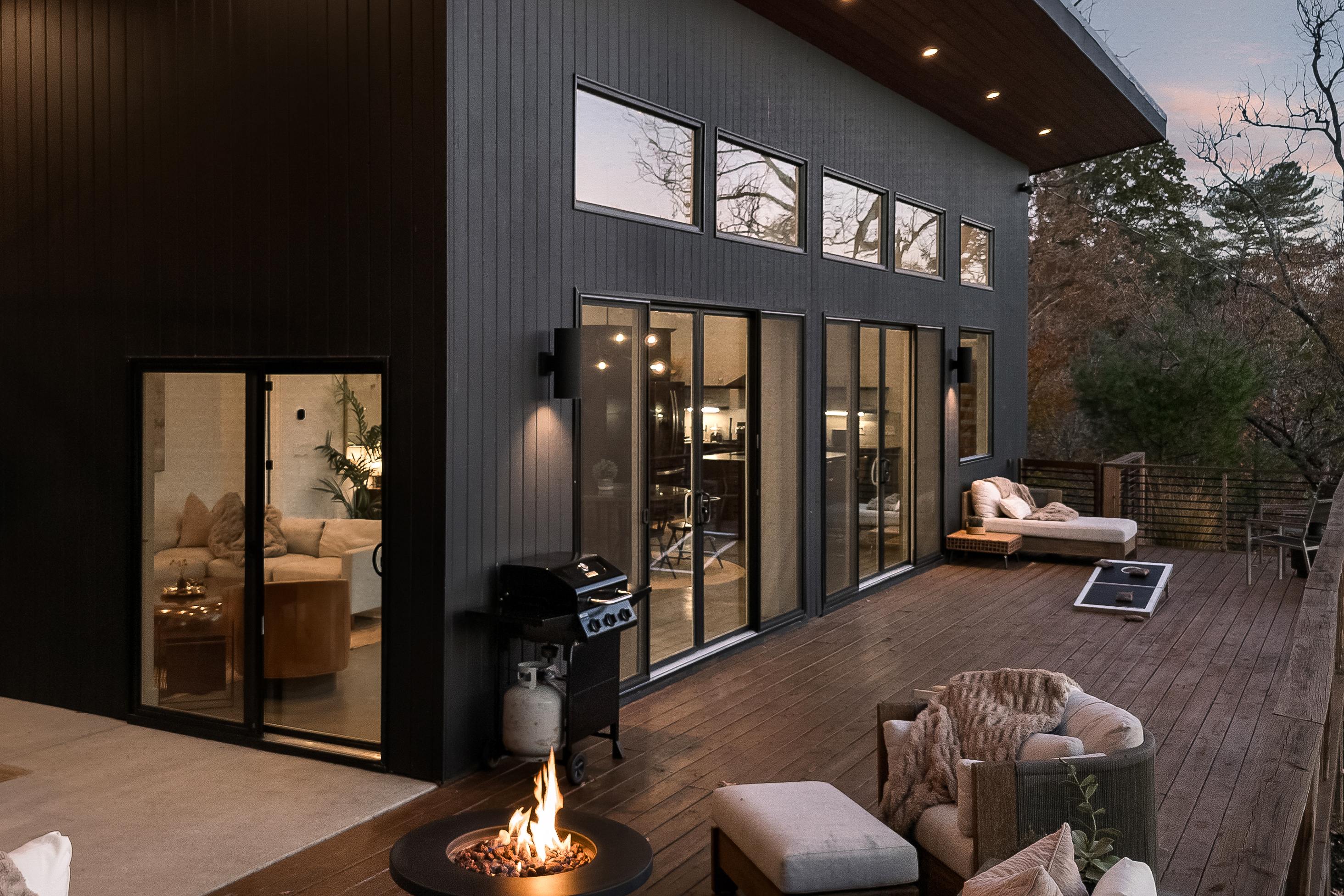 {Outdoor Lounge} The Glass House invites you to linger outside—cozy blankets, cornhole, giant Connect 4, and the forest glowing as twilight settles in. A mountain moment you won’t forget.