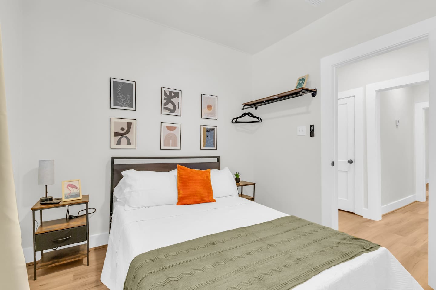 Queen bedroom with queen bed, exposed closet with hangers, room darkening shades and a TV.